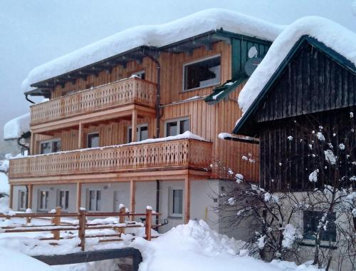 een groot houten huis met sneeuw op het dak bij dasGams in Gosau