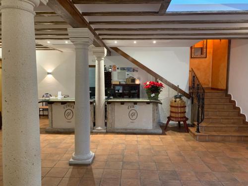 un hall avec un escalier et une table fleurie dans l'établissement Hostal El Palomar, à Tomelloso