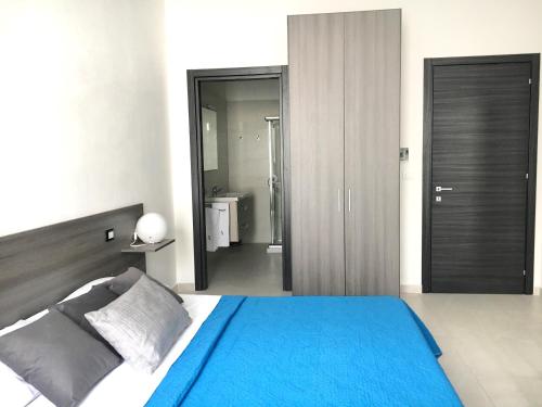 a bedroom with a blue bed and a bathroom at B&B Costa Azzurra in Porto Cesareo