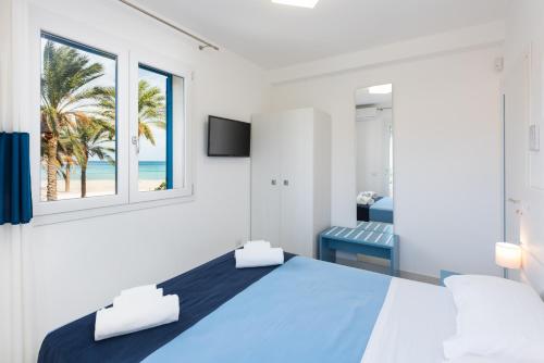 a bedroom with a blue bed with a view of the beach at Residence Le Palme in San Vito lo Capo