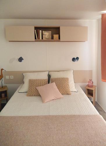 une chambre avec un grand lit avec des draps et des oreillers blancs dans l'établissement Mobil home à 100 m des plages dans camping 4 étoiles avec vue sur la montagne, à Canet