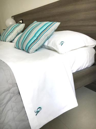 a bed with white sheets and pillows on it at B&B Costa Azzurra in Porto Cesareo