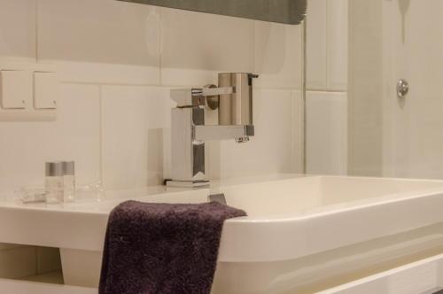 een badkamer met een wastafel en een bad met een paarse handdoek bij B&B de Ferver in Leeuwarden