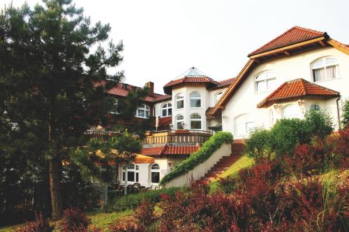a large white house with red roofs on a hill at Hotel Heidekrug in Grünplan