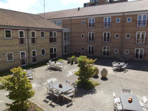 a courtyard with tables and chairs in front of a building at Montra Odder Parkhotel in Odder