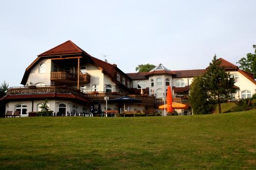 a large house with a green lawn in front of it at Hotel Heidekrug in Grünplan
