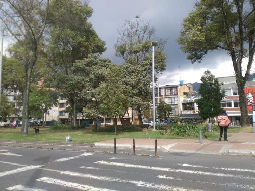 a person with an umbrella standing on the side of a street at Alojate y Descansa in Bogotá