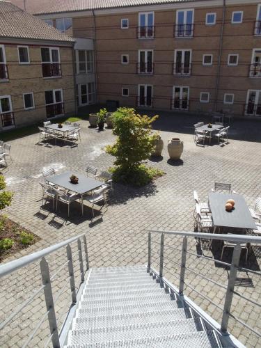 a courtyard with tables and benches and a building at Montra Odder Parkhotel in Odder