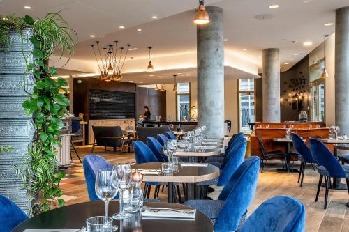un restaurant avec des tables et des chaises bleues ainsi qu'un bar dans l'établissement Hôtel Mercure Paris Gennevilliers, à Gennevilliers