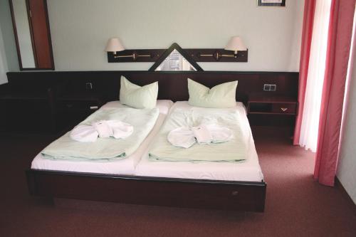 a bed with two towels on top of it at Hotel Heidekrug in Grünplan