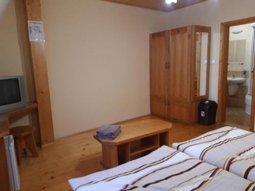 a room with two beds and a table and a television at Penzión Weinerovka Varín in Žilina