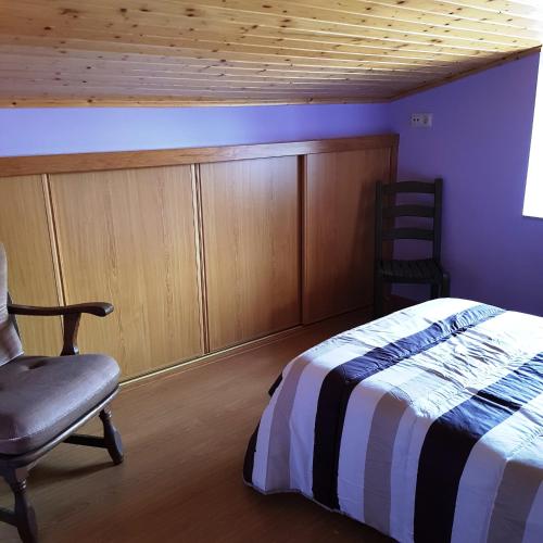 a bedroom with a bed and a chair at Moreiriña- Bentraces in Bentraces
