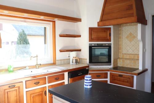 cocina con armarios de madera, fregadero y ventana en Eole Saint Bonnet, en Saint-Bonnet-en-Champsaur