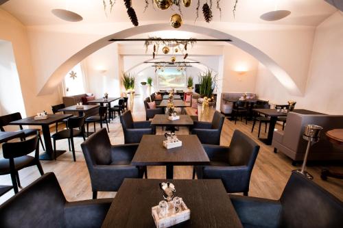 a restaurant with tables and chairs and a chandelier at Wallner - Hotel & Wirt in Arnoldstein