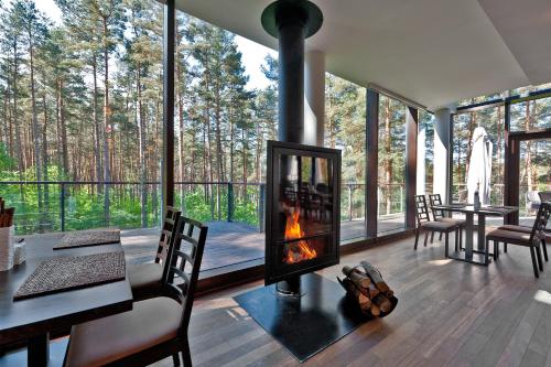 a living room with a fireplace and a table and chairs at Belvilis Hotel in Molėtai