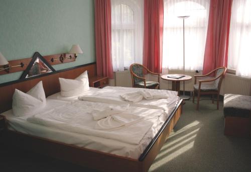 a hotel room with a large bed with white sheets at Hotel Heidekrug in Grünplan