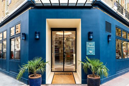 un bâtiment bleu avec deux plantes en pot devant lui dans l'établissement Hotel Residence Europe & Spa, à Clichy