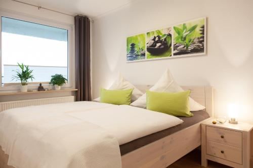 Un dormitorio con una cama con almohadas verdes y una ventana en Ferienwohnungen Tobian, en Glücksburg