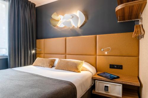 a hotel room with a bed and a light on the wall at Hotel Residence Europe & Spa in Clichy
