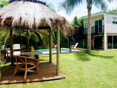 una terraza de madera con mesa y sombrilla de paja en CASA DE RELAX CON PISCINA en Paraná