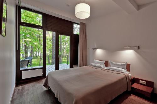 a bedroom with a large bed and a large window at Belvilis Hotel in Molėtai