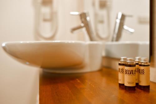 three bottles of essential oils on a wooden counter next to a sink at Belvilis Hotel in Molėtai