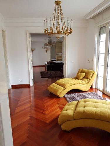 a living room with two yellow couches and a chandelier at Villa Dedinje in Belgrade