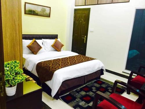a bedroom with a bed and a chair in a room at Hayyat Luxury Hotel Apartments in Lahore