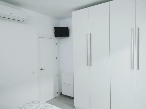 フエンヒロラにあるFUENGIROLA SWEET & BEACHの白いキャビネットと壁掛けテレビ付きのベッドルーム1室