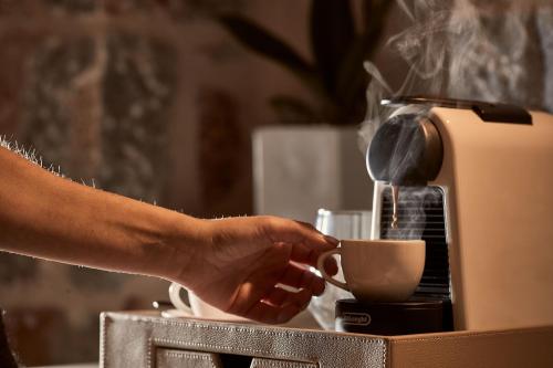 a person is making a cup of coffee at 100 Rizes Seaside Resort- Small Luxury Hotels of the World in Gythio