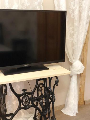 a television sitting on a table next to a curtain at Tulipán Villa Panzió in Szolnok