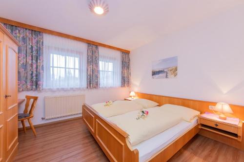 een slaapkamer met een bed, een bureau en 2 ramen bij Ferienwohnungen Christine in Waidring
