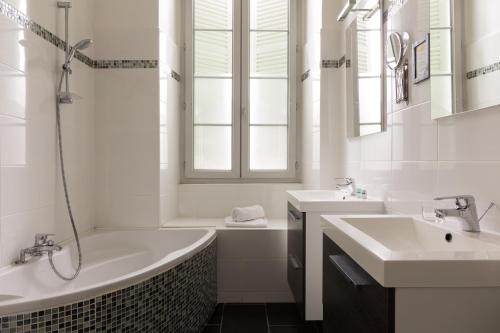 a white bathroom with two sinks and a tub and a tubermott at The Originals Boutique, Villa Montpensier, Pau (Inter-Hotel) in Pau