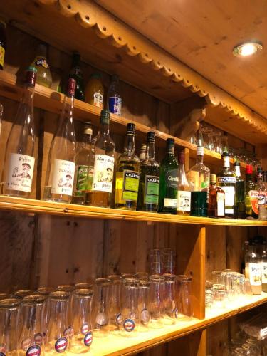a shelf filled with lots of bottles and glasses at Hôtel Restaurant de la Chaussée in Briançon