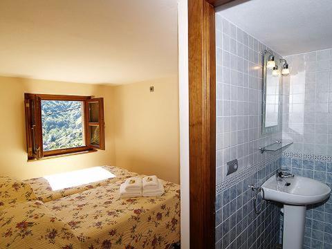 a bathroom with a bed and a sink with a window at El Caleyon in Bulnes