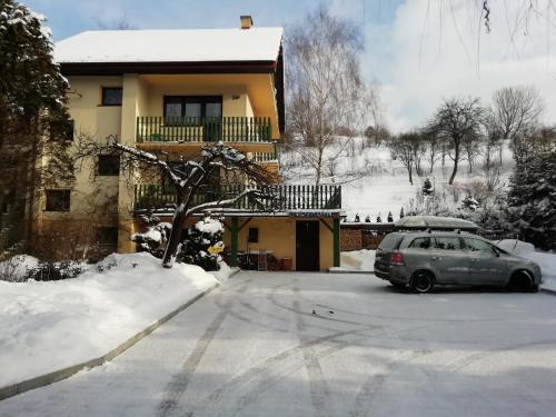 a car parked in front of a house in the snow at Willa Mirabelka in Piwniczna