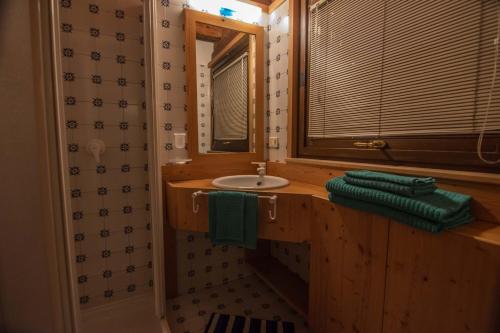 W łazience znajduje się umywalka i lustro. w obiekcie Tabiè Dli Cuuntini w mieście Dosoledo