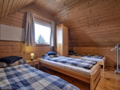 sypialnia z 2 łóżkami w drewnianym domku w obiekcie Domki Kaper Rewa w Rewie