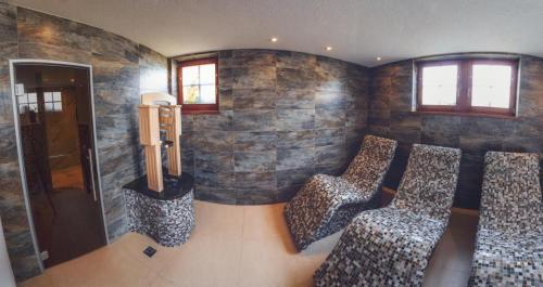 a room with three chairs in front of a stone wall at Penzion Pribisko in Zuberec