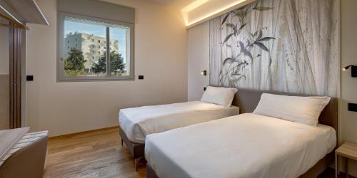 una camera d'albergo con due letti e una finestra di Park Hotel & Residence by The Cube a Fidenza