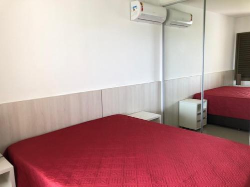 a bedroom with a red bed and a mirror at Apartamento frente à praia! in Florianópolis