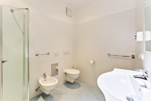 a white bathroom with a toilet and a sink at Gasserhof in Barbiano