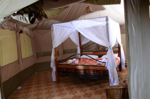 a bed with a canopy in a room at ELANGATA OLERAI LUXURY TENTED CAMP in Narok