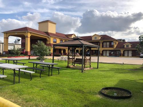 a group of tables and umbrellas in front of a building at Raintree Inn and Suites in Houston