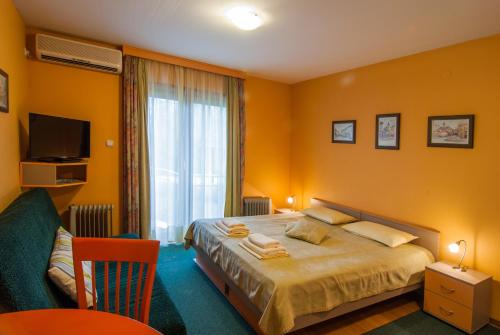 1 dormitorio con 1 cama, TV y ventana en Apartments Raj, en Vrnjačka Banja