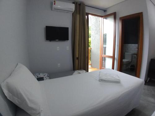 a bedroom with a white bed with a television on the wall at Refúgio 755 in Florianópolis
