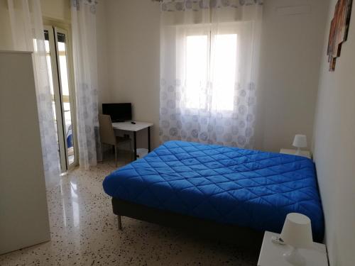 a bedroom with a blue bed and a desk and a window at Casagioiosa18 in Palermo
