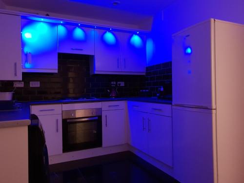 a kitchen with white cabinets and blue lights at Redwood House in Liverpool