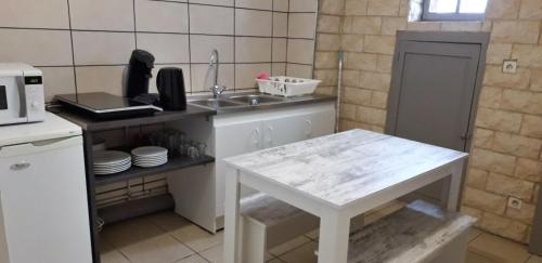 uma pequena cozinha com um lavatório e uma mesa em Appart comme chez soi em Pusignan