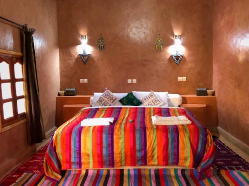 a bedroom with a large bed with a colorful blanket at Maison Hassan Merzouga in Merzouga